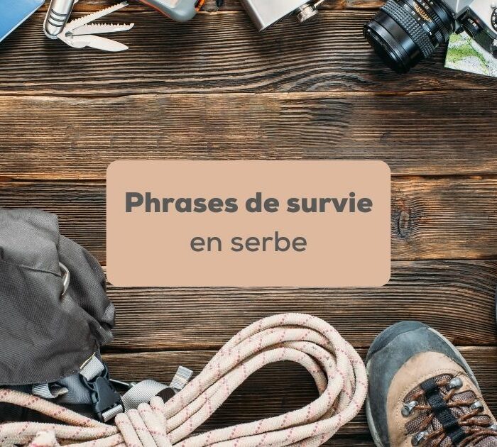 phrases de survie en serbe Kit de survie avec corde, chaussures de randonnées, carnet, sac, appareil photo et lampe de poche sur fond couleur bois