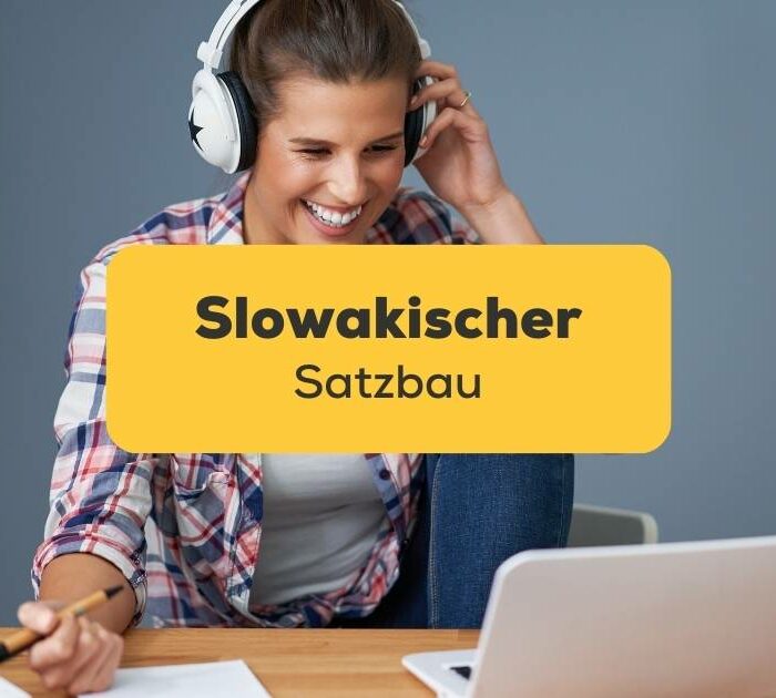 Junge Frau sitzt am Schreibtisch mit einem Laptop und Kopfhörern, sie lernt Slowakisch mit der Ling-App.