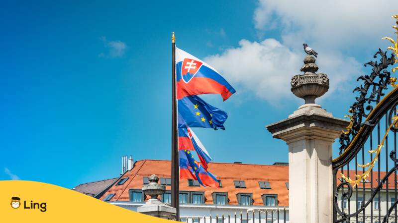 Slowakische und europäische Flaggen wehen vor einem Staatsgebäude. Lerne mit der Ling-App die slowakische Sprache.