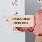 prononciation en albanais femme professeur enseignant la prononciation des lettres devant un tableau blanc