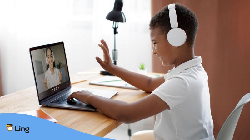 Learn French online - A photo of a young boy waving to her French teacher on a laptop.