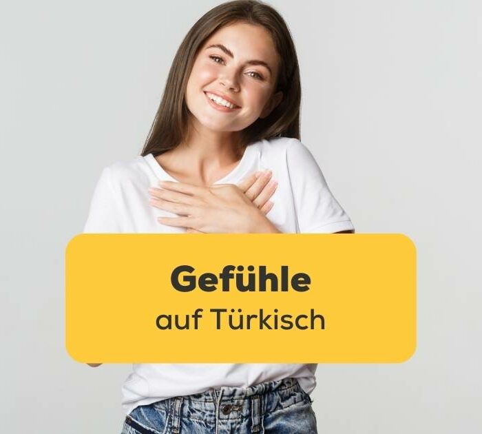 Berührte glückliche junge Frau, die lächelt, die Hände auf der Brust hält und sich dankbar fühlt. Lerne über 30 großartige Vokabeln, die du kennen solltest um Gefühle auf Türkisch auszudrücken. Lerne Türkisch mit der Ling-App.