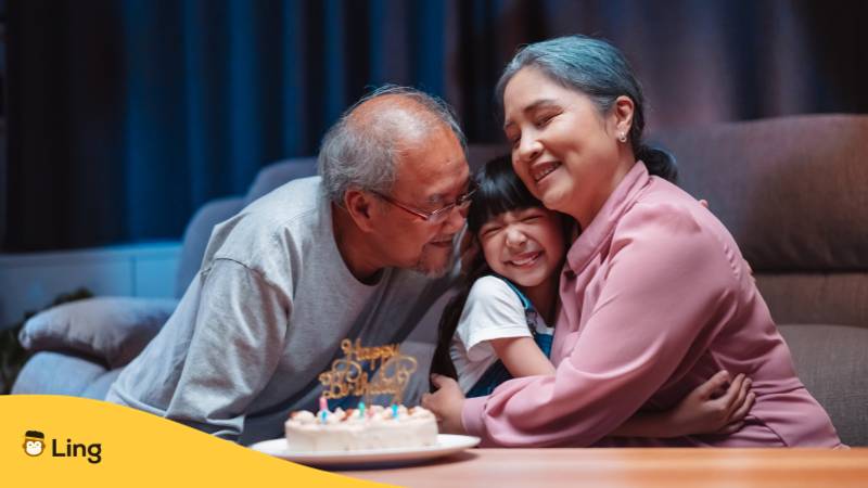 Philippinische Großeltern kuscheln mit Enkeltochter. Lerne Tagalog Familienwortschatz mit der Ling-App.
