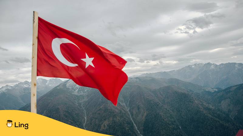 Flagge der Türkei über dem Berg. Ist Türkisch schwer zu lernen? Erfahre 6 motivierende Gründe, warum es einfacher ist, als du denkst mit der Ling-App.
