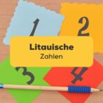 Vier bunte Blätter mit Zahlen von 1 bis 4 und Stift auf Holztisch. Der beste Leitfaden, um litauische Zahlen zu lernen!