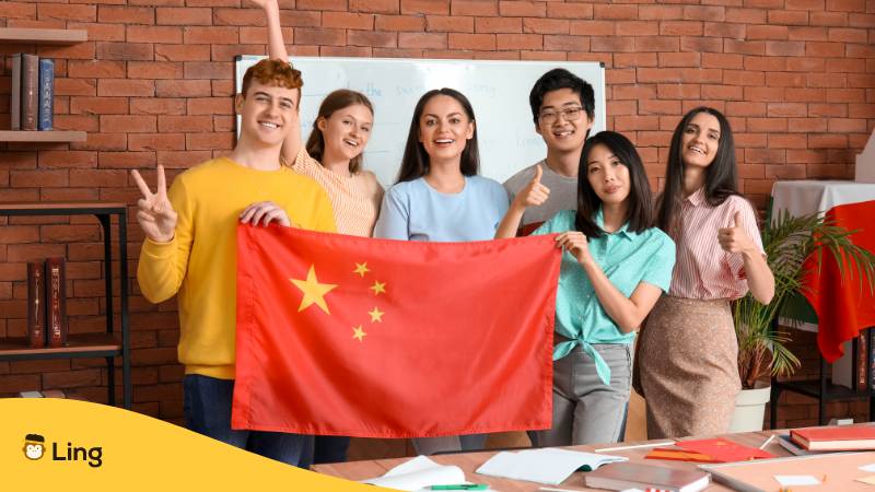 Junge Studenten mit chinesischer Flagge in der Sprachschule. Erfahre, warum es kein Chinesisch bei Babbel gibt? Und entdecke die beste App, um Chinesisch 2024 zu lernen!