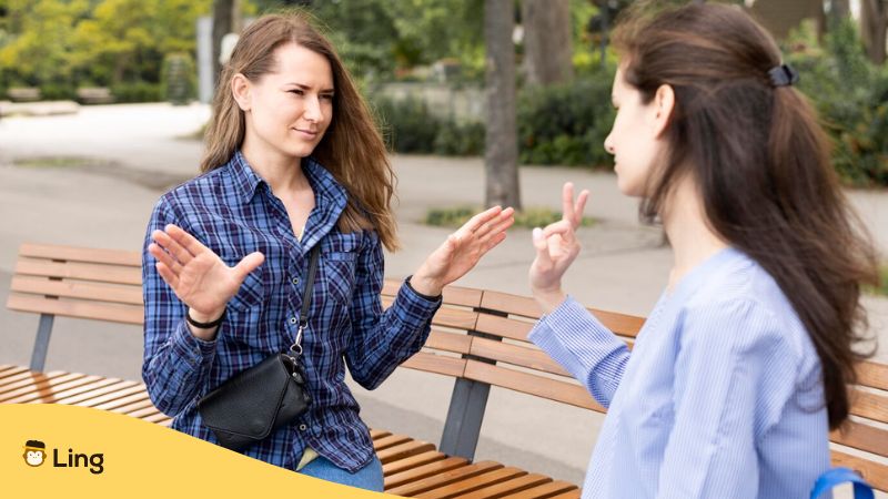 Best apps to learn sign language - A photo of two women sitting on a bench doing sign language.