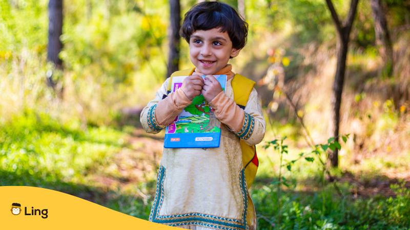 Kleines Mädchen hält glücklich ein Buch in der Hand und will sich auf Urdu bedanken