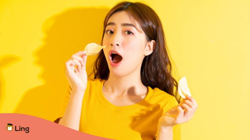 Junges asiatisches Mädchen isst Snack auf gelbem Hintergrund. Entdecke über 25 leckere koreanische Snacks mit Ling!
