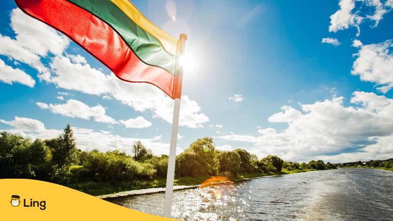 Die litauische Flagge weht an einem Schiff, welches den Fluss entlang schwimmt. Entdecke 10+ nützliche litauische Sätze für Reisen!