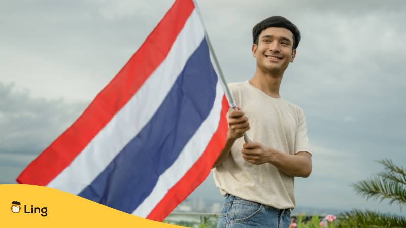 Junger Mann hält thailändische Nationalflagge. Entdecke 8 interessante Thai Nationalsymbole mit Ling!
