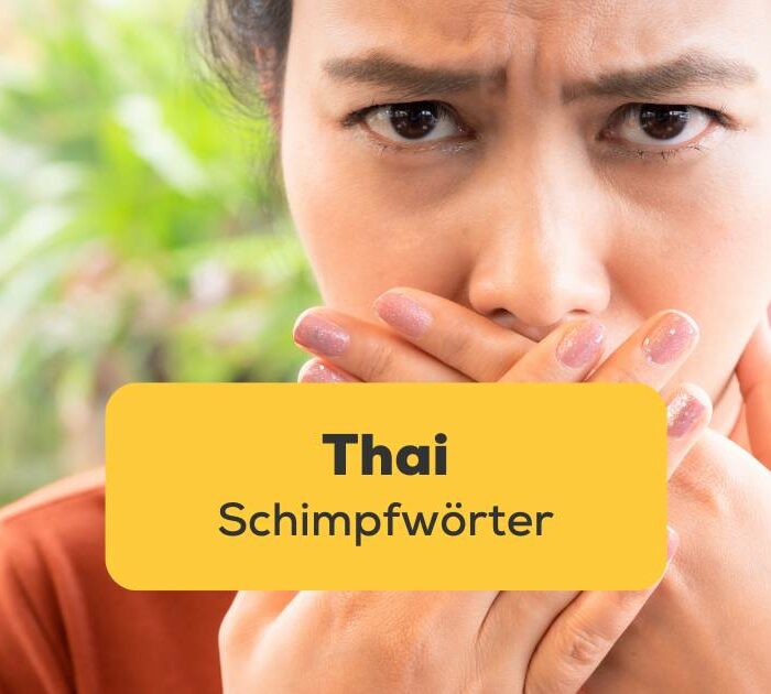 Thai Frau hat Thai Schimpfwörter verwendet und hält sich vor Scham Hände vor den Mund. Dein Guide zum Verstehen von Thai Schimpfwörtern