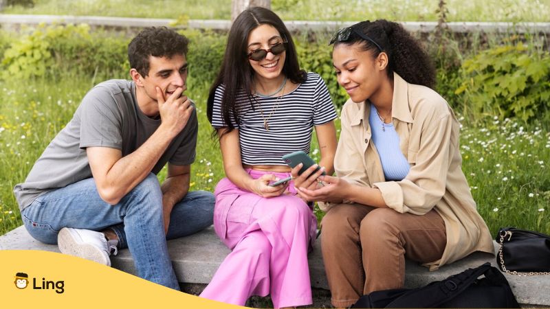Best language learning software - A photo of three students using their phones outdoor.