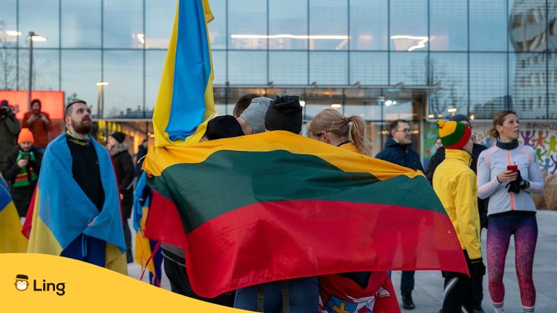 An image of a big Lithuanian flag draping over people