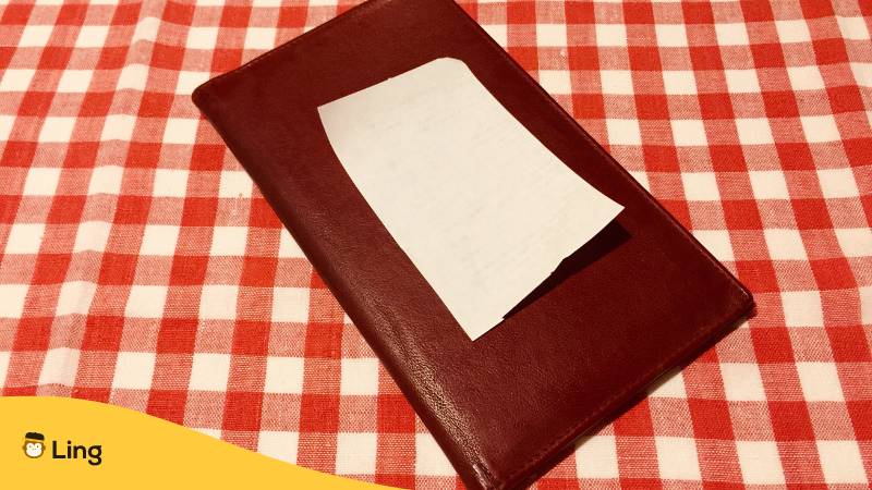 Rechnung auf einer rot-weisen Tischdecke. Die besten Tipps & Tricks für Essen bestellen auf Kroatisch.
