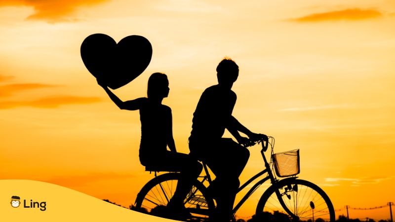 Silhouette of a couple on a bicycle holding a heart