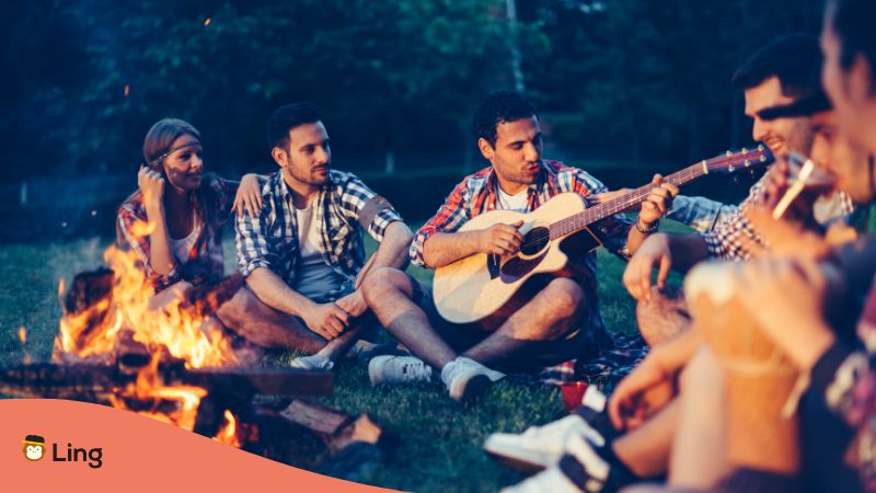 Filipino music vocabulary - A photo of friends around a campfire with a guitar.