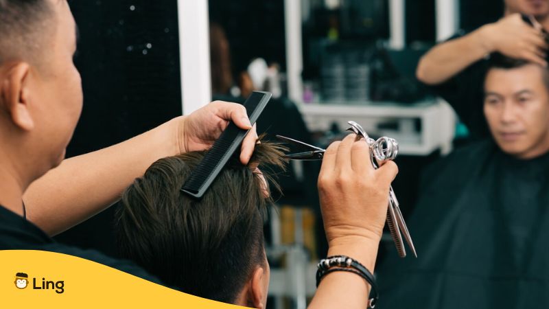 A photo of a male hair salon customer getting a haircut from a barber.