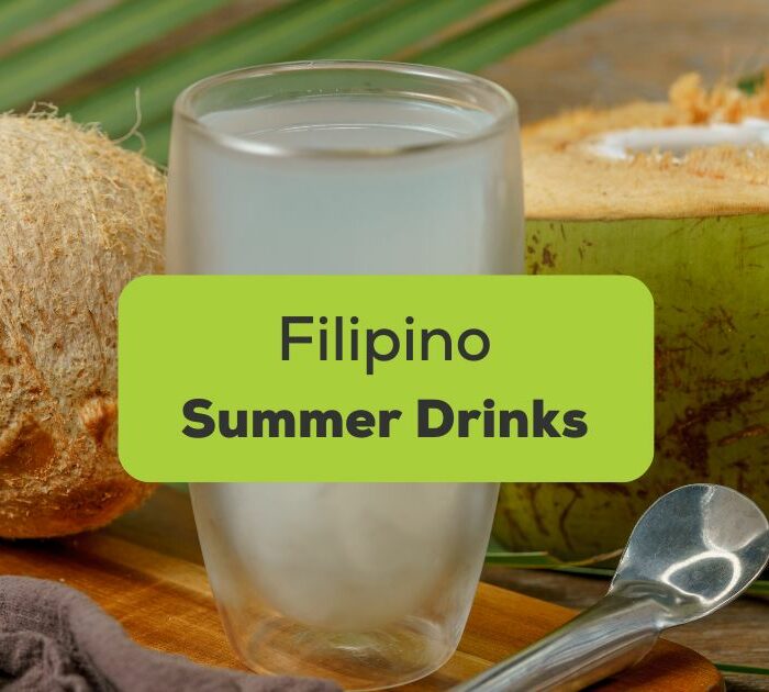 Filipino summer drinks - A glass of buko juice surrounded by coconut and palm leaves on a wooden surface.