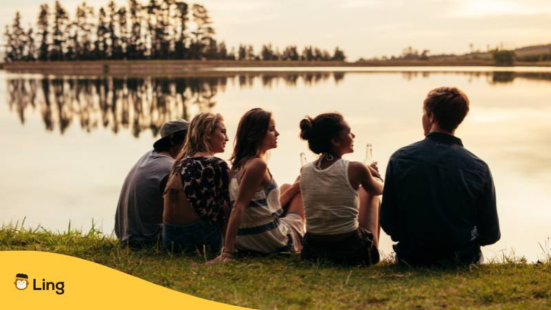 Freunde Sitzen Gemeinsam Am See Während Des Sonnenuntergangs