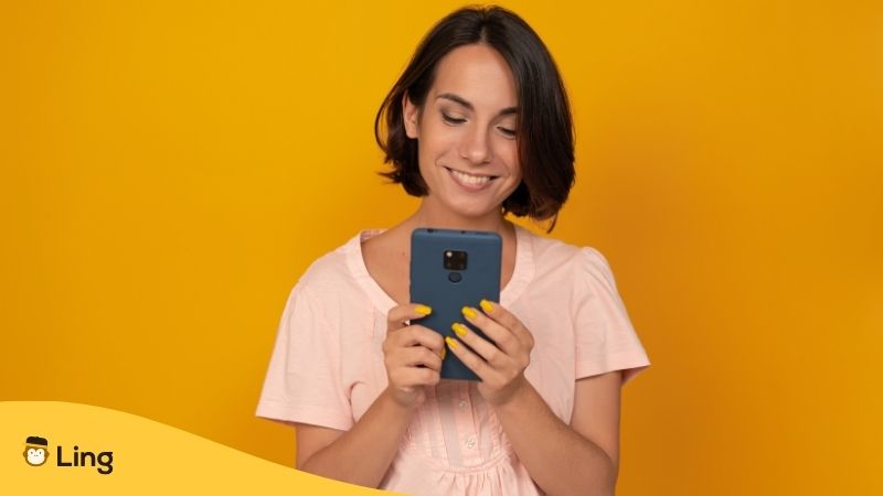 Mujer Usando El Celular Y Sonriendo, Con Un Fondo Amarillo