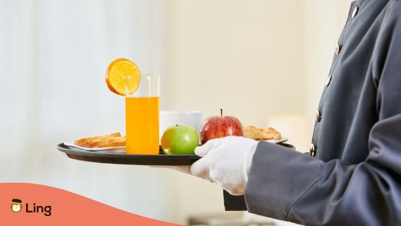 Close-Up Of A Waiter's Gloved Hands Carrying A Room Service Tray With Food