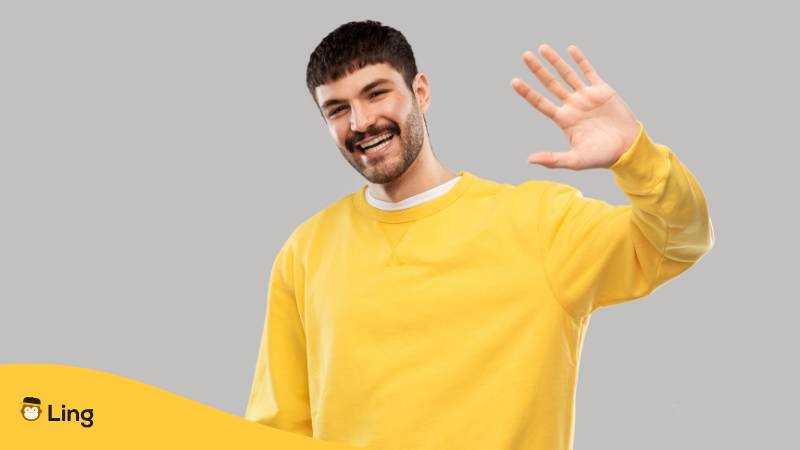 Junger Mann In Gelben Sweater Winkt