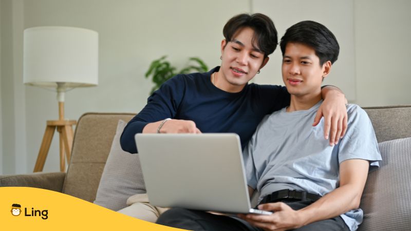 same sex thai couple watching movie on laptop