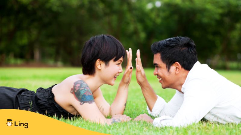 thai man and chinese woman couple lying on grass