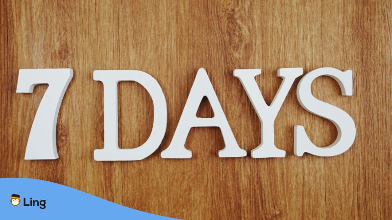 7 Days Written On White Wooden Blocks Against A Wooden Floor