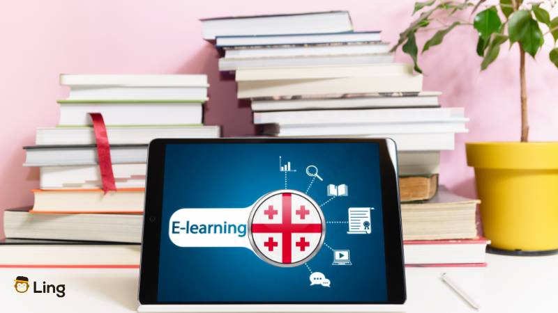 Tablet Mit E-Learning Schriftzug Und Georgischer Flagge Vor Bücherstapel