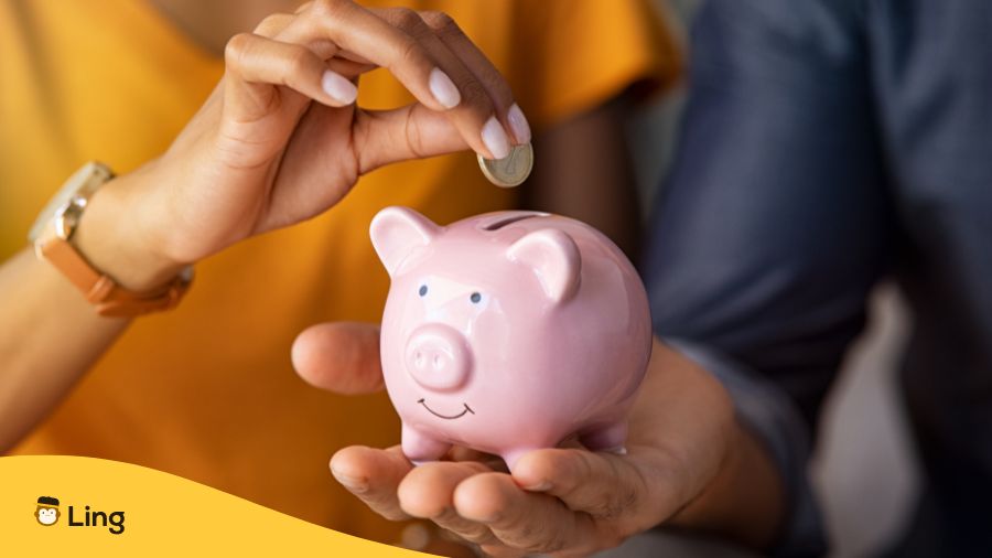 Someone Putting A Coin On A Piggy Bank - Saving Money By Using Affordable Language Apps