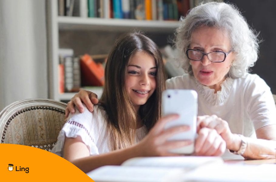 En Pige, Der Glædestrålende Viser Sin Bedstemor Sine Nepalesiske Lektioner På Mobiltelefonen
