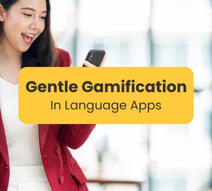 A woman looking at her phone making a fist with her hand as in triumph - Gentle gamification in language apps