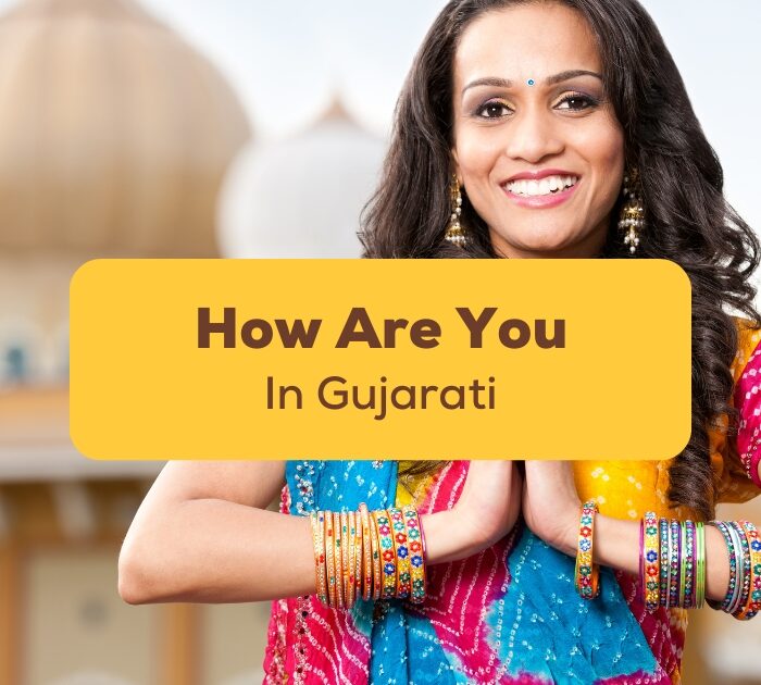 An Indian woman in traditional clothes doing namaste and asking How are you in Gujarati