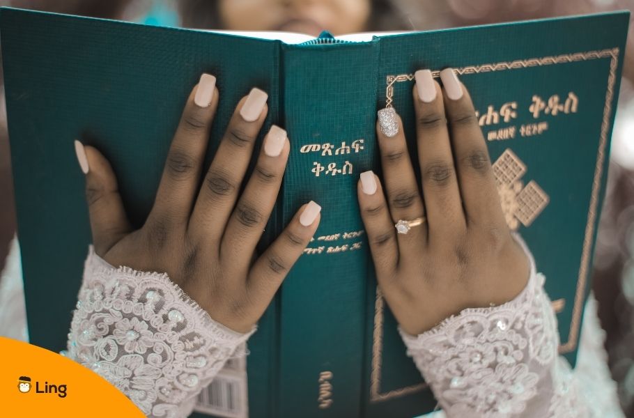 Someone Holding A Book Written In Amharic