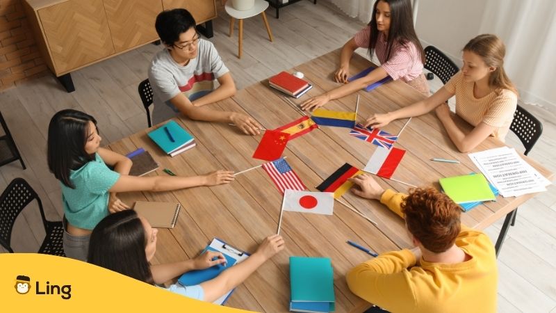 Jóvenes Aprendiendo Idiomas Con Banderas De Distintos Países Sobre La Mesa