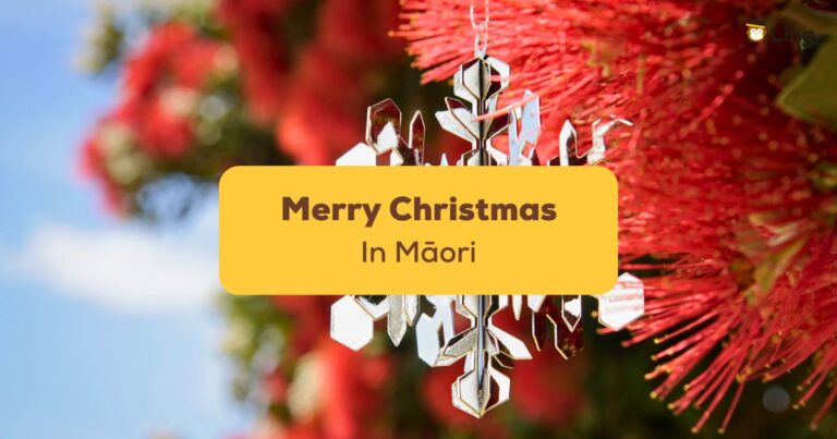 A Close Up Image Of A Silver Snowflake Christmas Ornament Hanging On A Blooming Pōhutukawa Tree - Merry Christmas In Māori