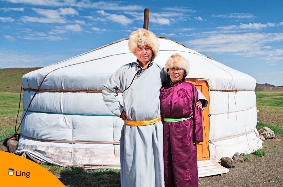 Mongolian Couple In Traditional Clothing Standing In Front Of A Yurt