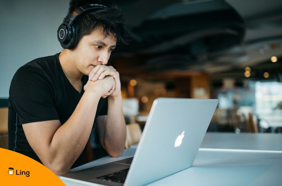 A Man Wearing Headphones Sitting In Front Of A Laptop