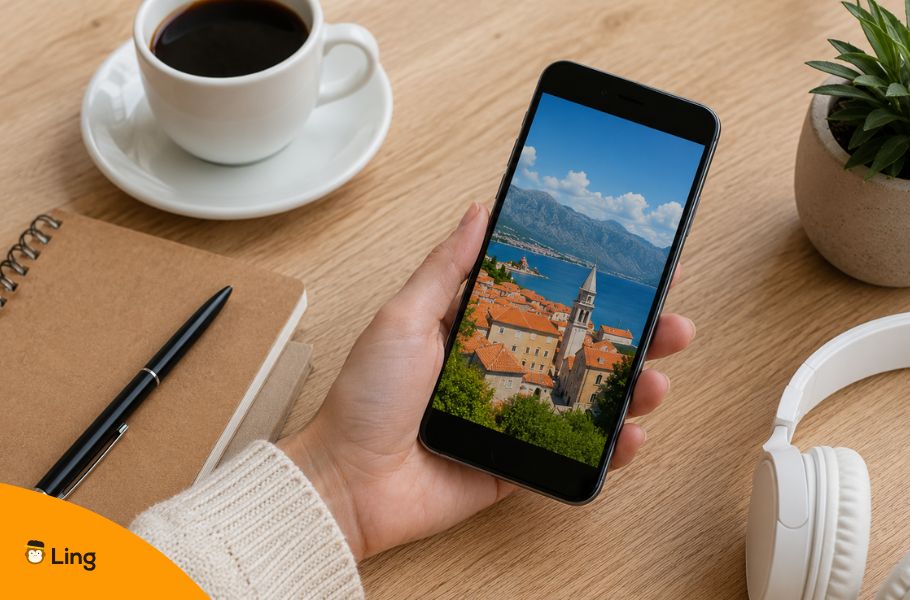 A Hand Holding A Smartphone Displaying A Coastal Mediterranean Town