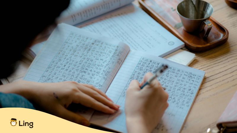 Personne Écrivant Des Caractères Kanji Sur Un Cahier Blanc À Carreaux