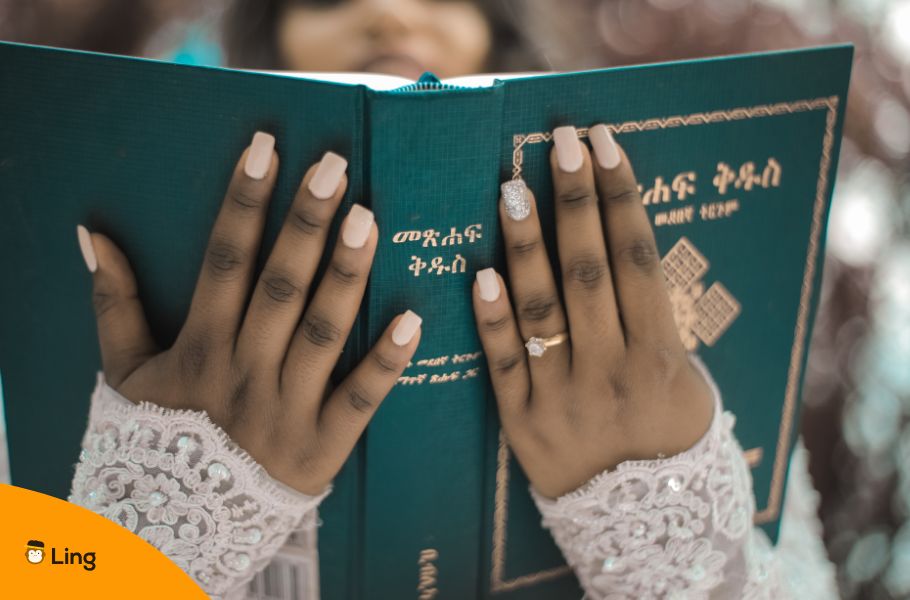 Hands Holding An Amharic Bible With Gold Geʽez Lettering On The Cover