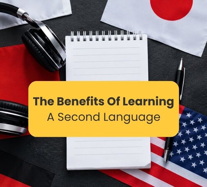 benefits of learning a second language - Various world flags on a dark table with a headset and a blank notebook