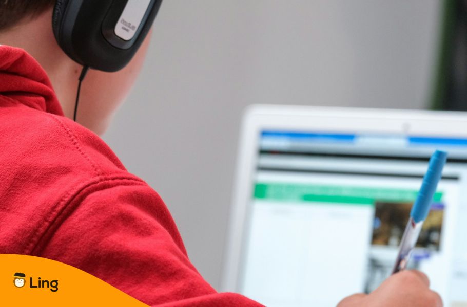 Someone Learning A Language On A Computer Holding A Pen