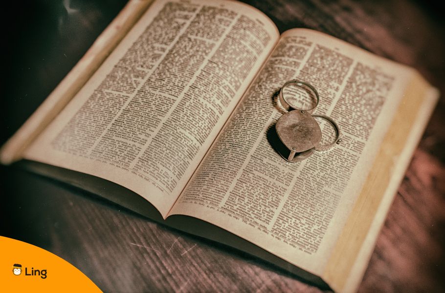 An Image Of An Old Dictionary With A Small Magnifying Glass
