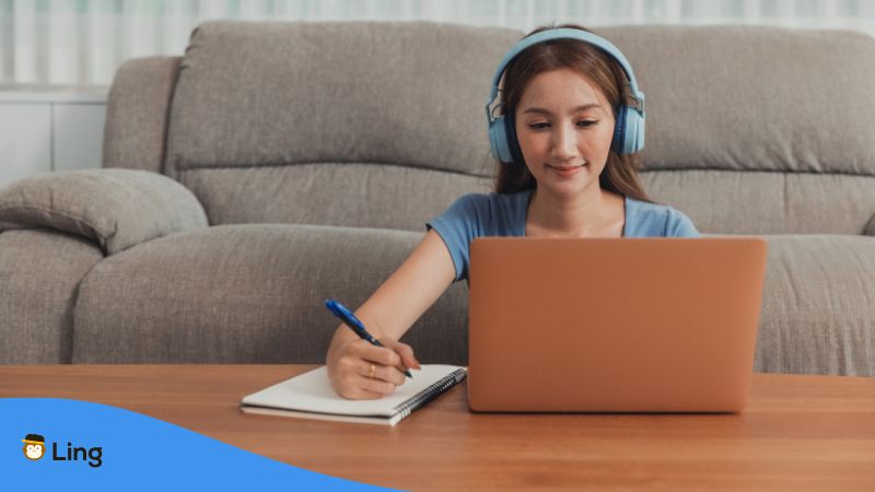 Junge Frau Sitzt Mit Kopfhörern Vor Macbook Und Lernt Eine Neue Sprache