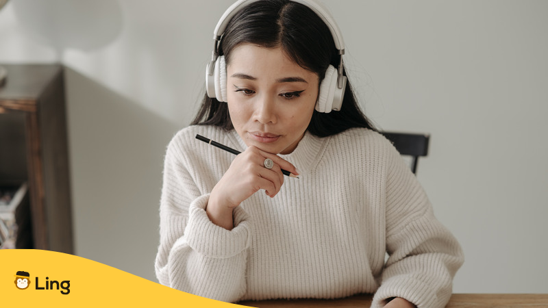 ヘッドホンでセルビア語の発音を聞きながら勉強する女性