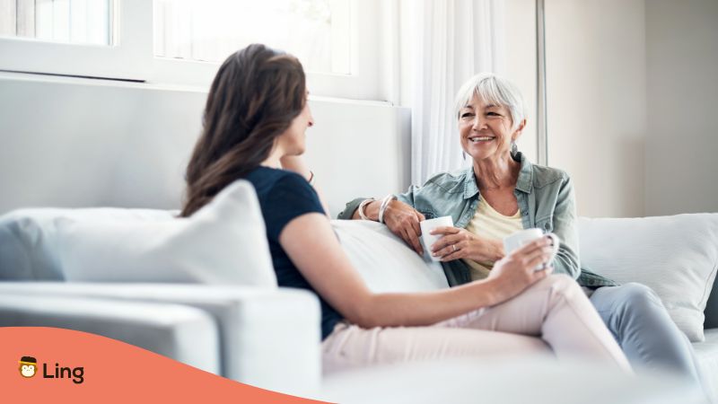 Zwei Frauen Sitzen Auf Dem Sofa. Eine Frau Fragt: Wie Geht Es Dir Auf Serbisch?